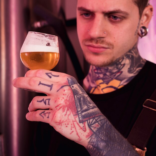 Uomo con tatuaggi che producono birra artigianale