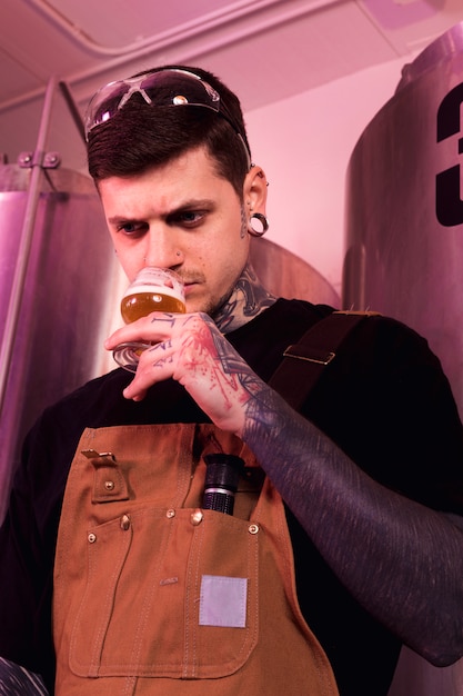 Uomo con tatuaggi che producono birra artigianale