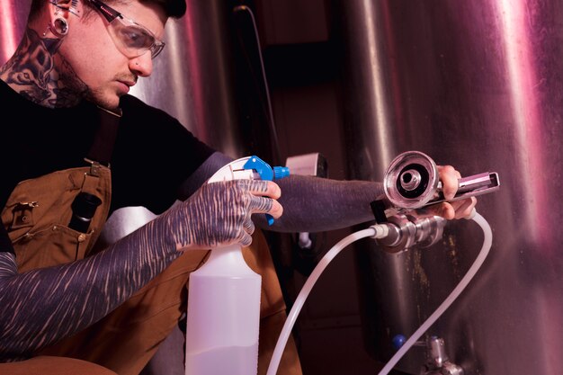 Uomo con tatuaggi che producono birra artigianale