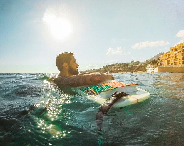 Uomo con tavola da surf in acqua blu