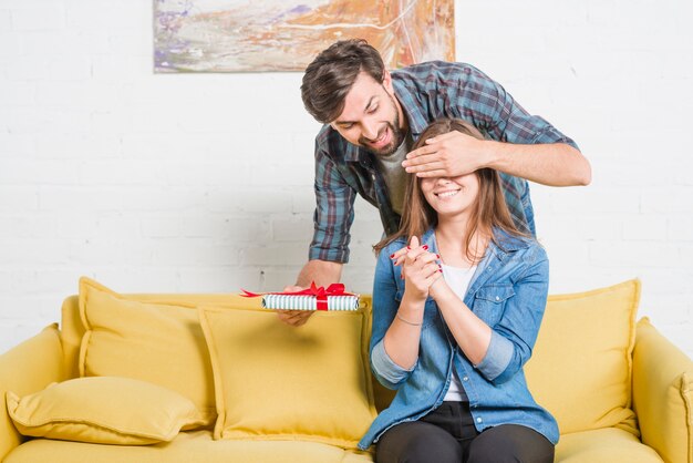 Uomo con un regalo di compleanno che copre gli occhi della sua ragazza