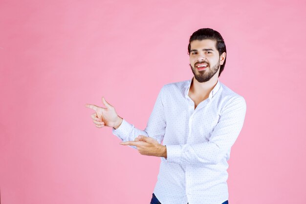 Uomo con una camicia bianca che indica il lato sinistro.