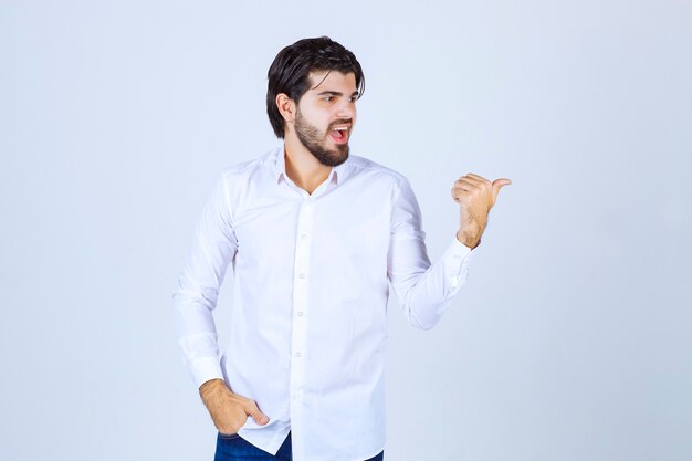 Uomo con una camicia bianca che punta all'indietro