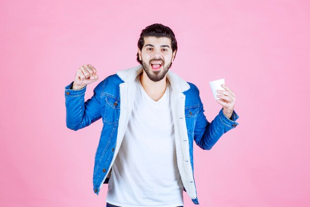 Uomo con una tazza di caffè che mostra il pugno