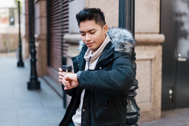 Uomo con una tazza di caffè guardando il suo orologio