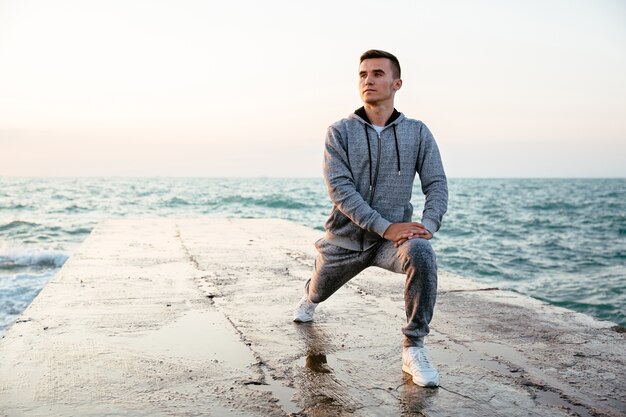 Uomo concentrato Pensive in sportswear facendo affondi, stretching