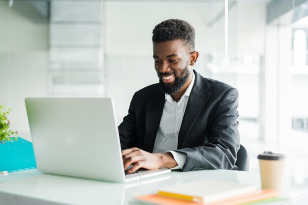 Uomo d'affari afroamericano premuroso che utilizza computer portatile, progetto di riflessione, strategia aziendale, dirigente perplesso dei dipendenti che esamina lo schermo del computer portatile, lettura della posta elettronica, presa della decisione all'ufficio