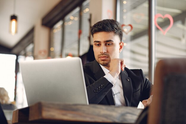 Uomo d'affari alla moda che lavora in un bar e utilizzare il computer portatile