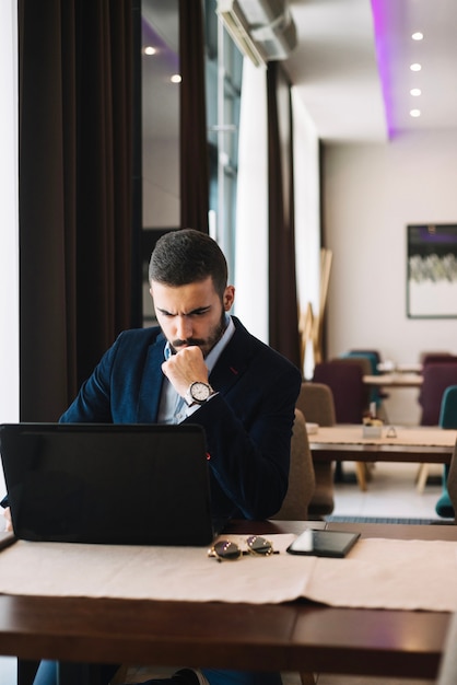 Uomo d&#39;affari alla moda con il computer portatile in caffè