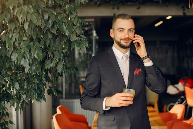 Uomo d'affari alla moda in un vestito nero che lavora in un caffè