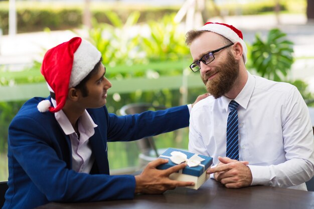 Uomo d&#39;affari allegro che dà il contenitore di regalo al collega