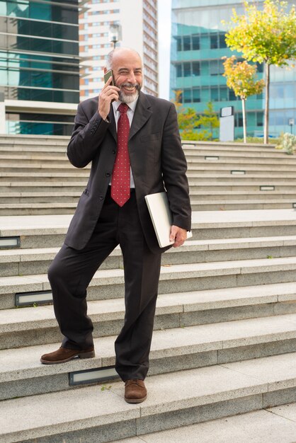 Uomo d'affari allegro con smartphone e laptop