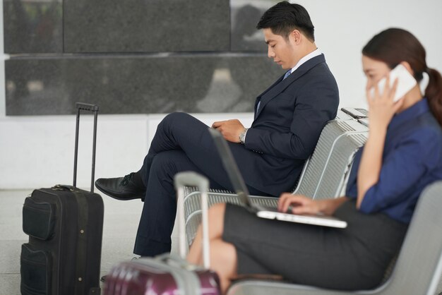 Uomo d'affari asiatico bello che aspetta nell'aeroporto