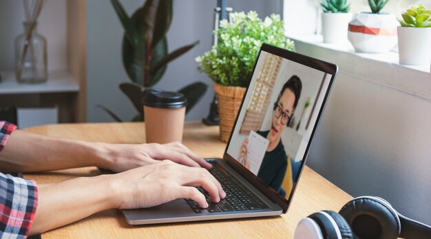 Uomo d'affari asiatico che lavora in remoto da casa e webinar per riunioni di videoconferenza virtuale con colleghi uomini d'affari. distanza sociale a casa concetto di ufficio.