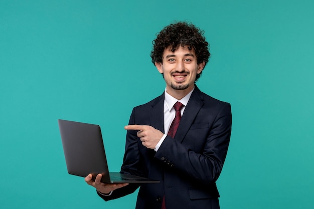 Uomo d'affari bello carino giovane ragazzo in abito nero e cravatta rossa sorridente con il computer portatile