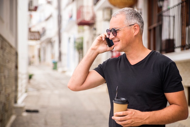 Uomo d&#39;affari bello che comunica sul telefono e bere il caffè