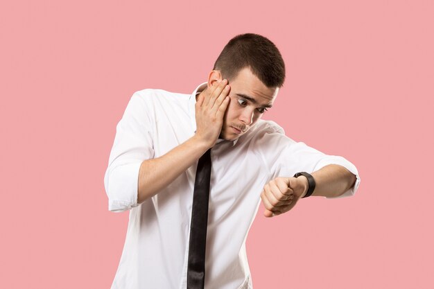 Uomo d'affari bello che controlla il suo orologio da polso isolato sul rosa. Wow. Attraente ritratto frontale a mezzo busto maschile