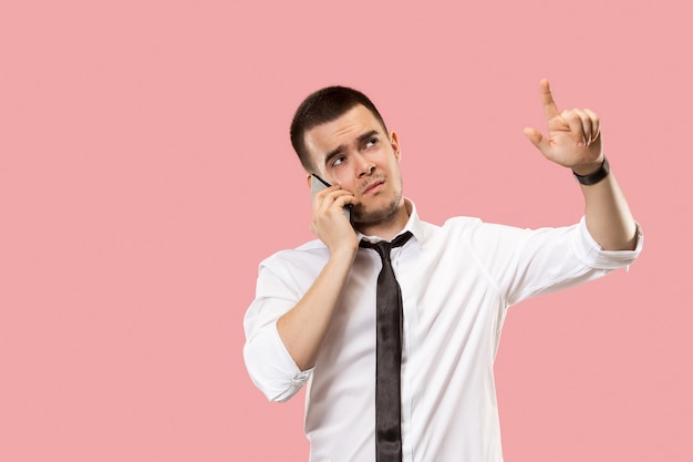 Uomo d'affari bello con il telefono cellulare. giovane uomo d'affari in piedi isolato su sfondo rosa studio.