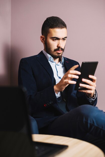 Uomo d&#39;affari bello guardare la tavoletta