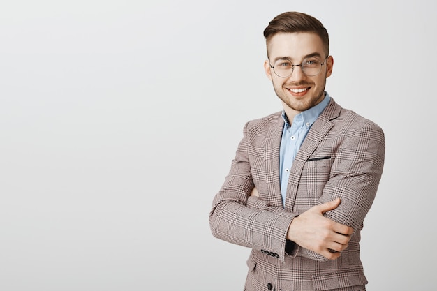 Uomo d'affari bello in vestito e occhiali attraversano il petto e lo sguardo delle braccia