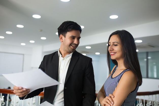 Uomo d&#39;affari bello sorridente che mostra rapporto annuale al collega