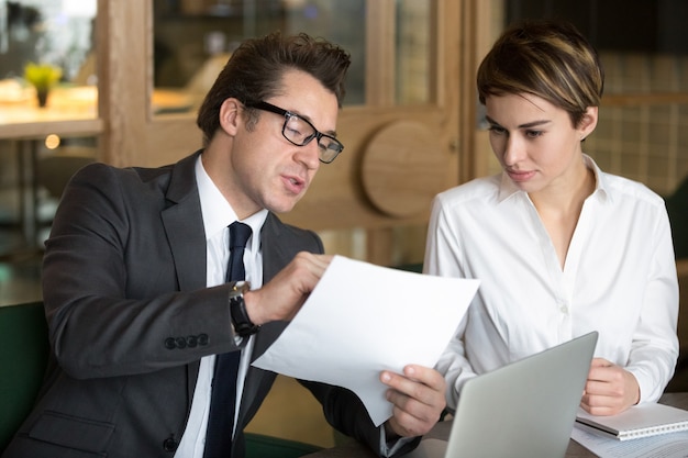 Uomo d&#39;affari che consulta il collega femminile sulle condizioni del contratto