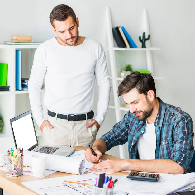 Uomo d&#39;affari che esamina il suo collega che lavora al grafico