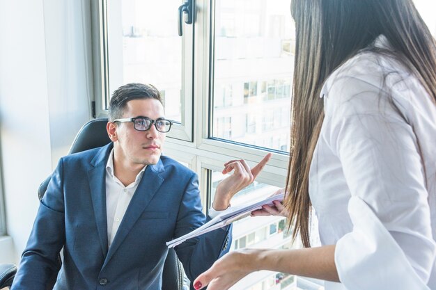 Uomo d&#39;affari che fa le domande alla donna di affari nell&#39;ufficio