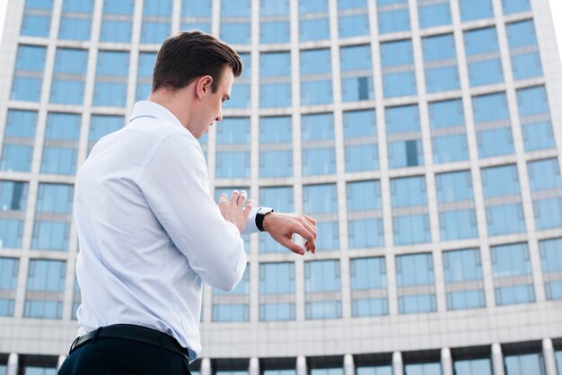 Uomo d'affari che guarda orologio vicino alla costruzione