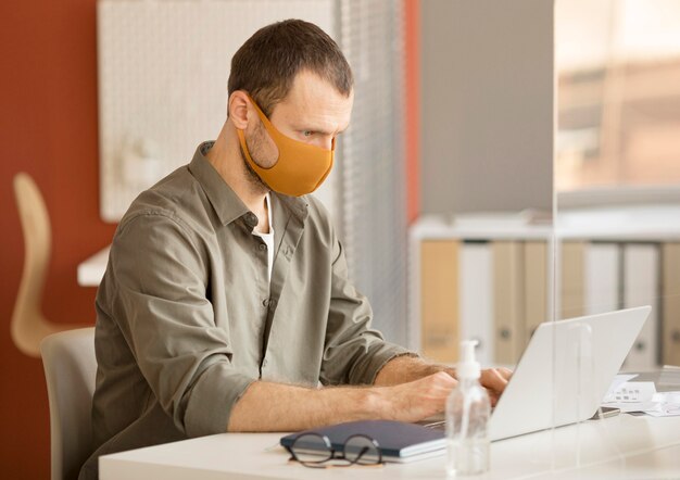 Uomo d'affari che indossa la maschera per il viso in ufficio