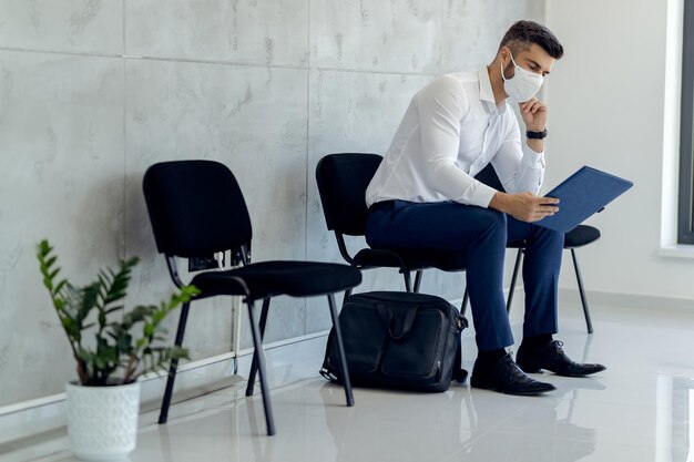 Uomo d'affari che indossa una maschera protettiva durante l'attesa o un colloquio di lavoro