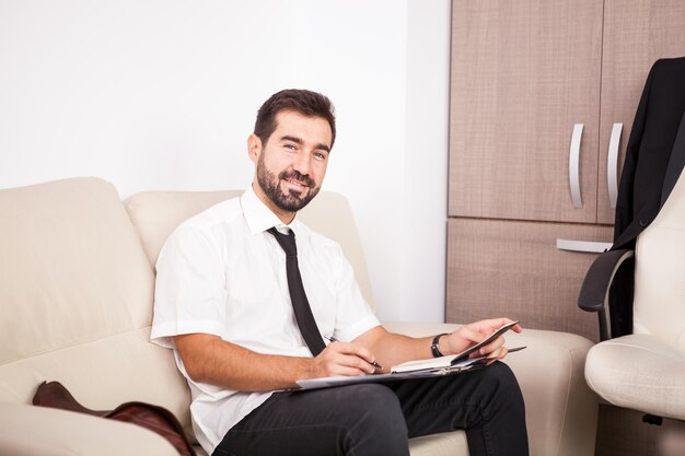 Uomo d'affari che lavora in ufficio sul divano mettendo lunghe ore di lavoro. Imprenditore in ambiente professionale