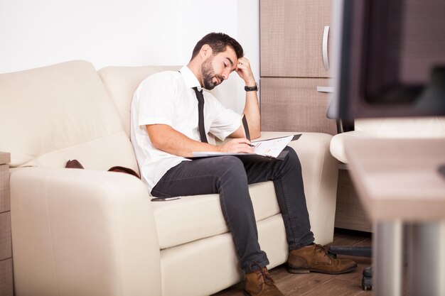 Uomo d'affari che lavora in ufficio sul divano mettendo lunghe ore di lavoro. Imprenditore in ambiente professionale