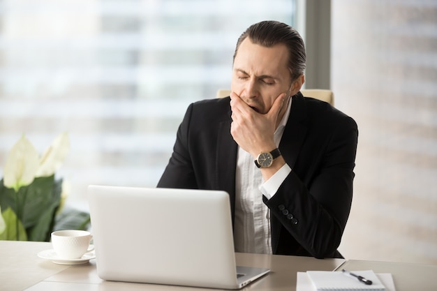 Uomo d&#39;affari che lotta con la sonnolenza sul lavoro