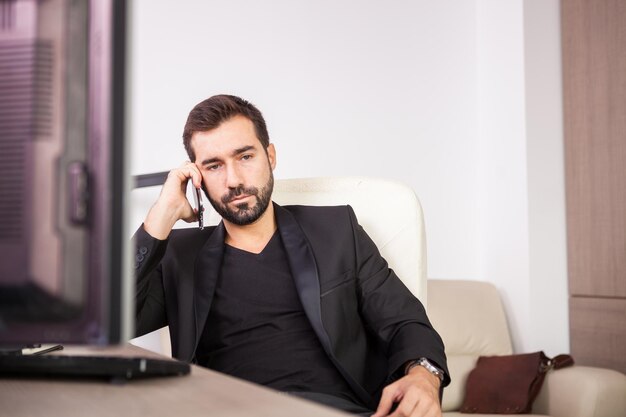 Uomo d'affari che parla al telefono mentre lavora nel suo ufficio. Imprenditore in ambiente professionale