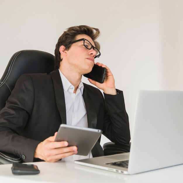 Uomo d&#39;affari che parla con il cellulare mentre si utilizza la tavoletta digitale