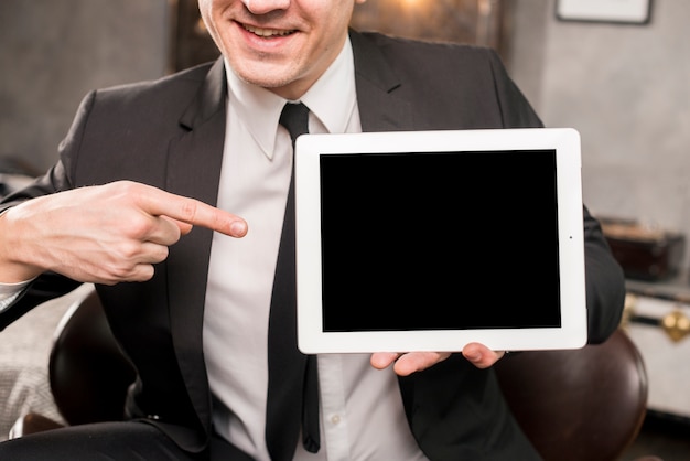 Uomo d&#39;affari che punta al tablet con schermo vuoto