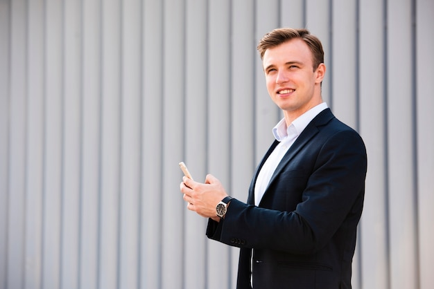 Uomo d'affari che usando il suo distogliere lo sguardo del telefono