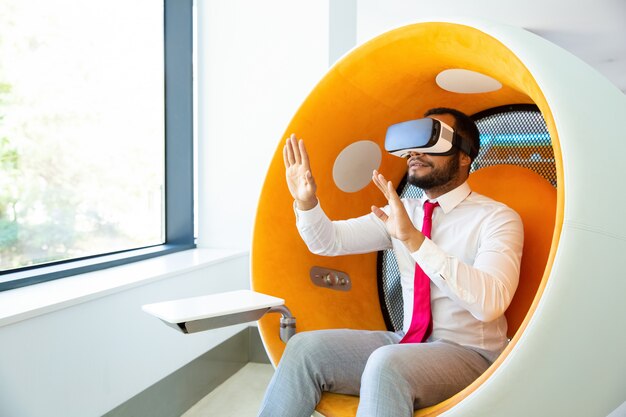 Uomo d'affari che utilizza la cuffia avricolare di realtà virtuale nell'ufficio