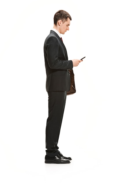 Uomo d'affari con cartella in chat sullo smartphone isolato sul muro bianco