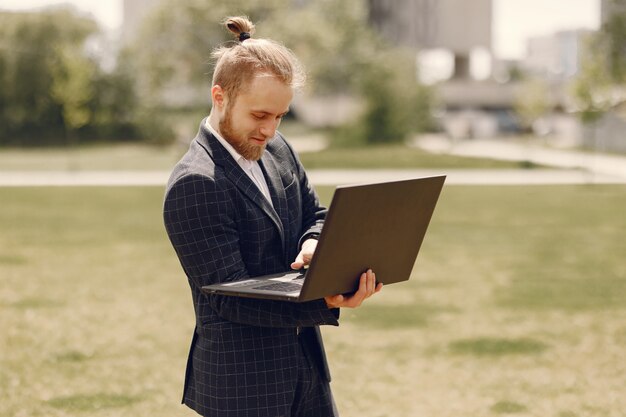 Uomo d'affari con il computer portatile in una città estiva