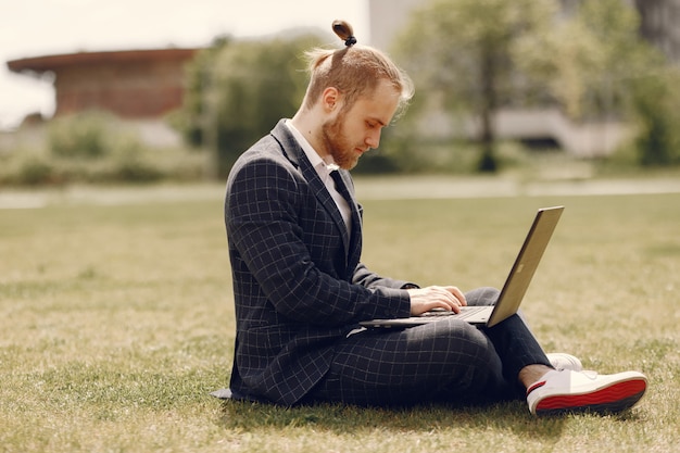 Uomo d'affari con il computer portatile in una città estiva