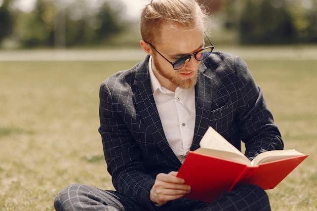 Uomo d'affari con il libro seduto in una città estiva