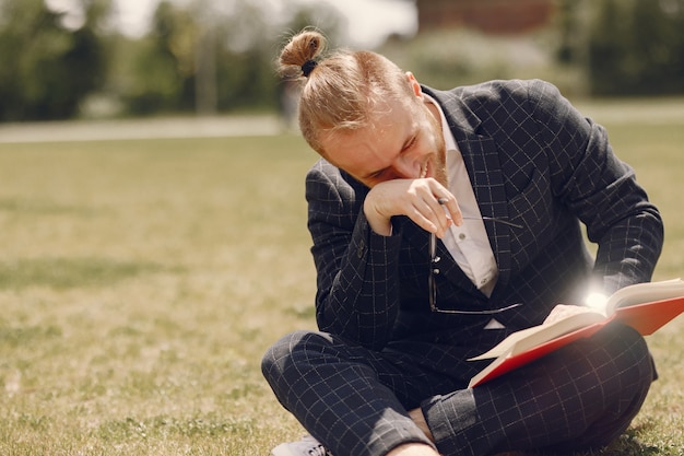 Uomo d'affari con il libro seduto in una città estiva