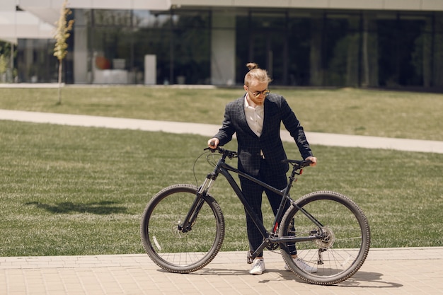 Uomo d'affari con la bicicletta in una città estiva