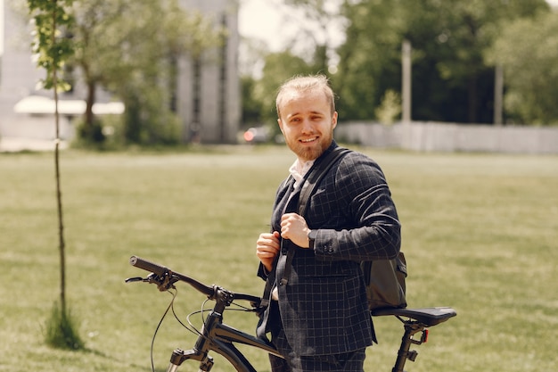 Uomo d'affari con la bicicletta in una città estiva