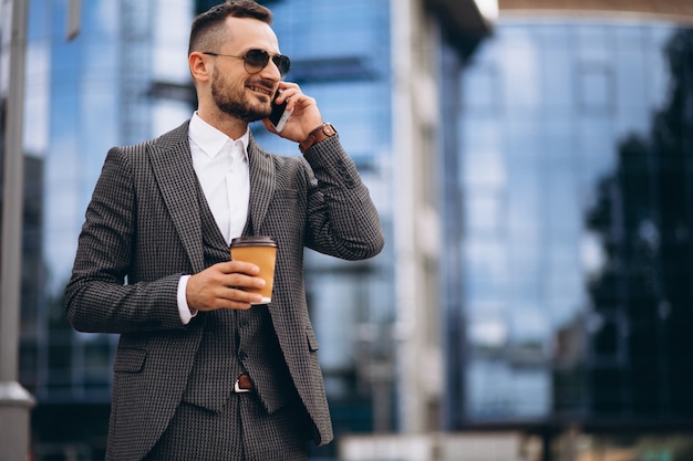 Uomo d&#39;affari con telefono bere caffè al di fuori del grattacielo