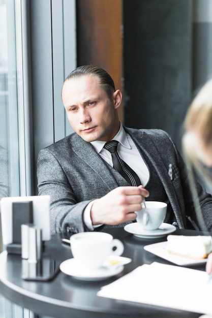 Uomo d&#39;affari contemplato con la tazza di caffè che si siede nel caf�