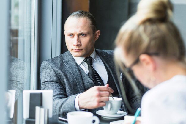 Uomo d&#39;affari contemplato con la tazza di tè che si siede nel ristorante