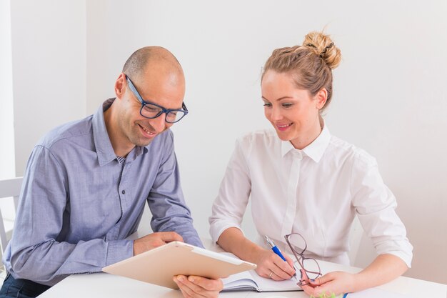 Uomo d&#39;affari e donna di affari sorridenti che esaminano compressa digitale